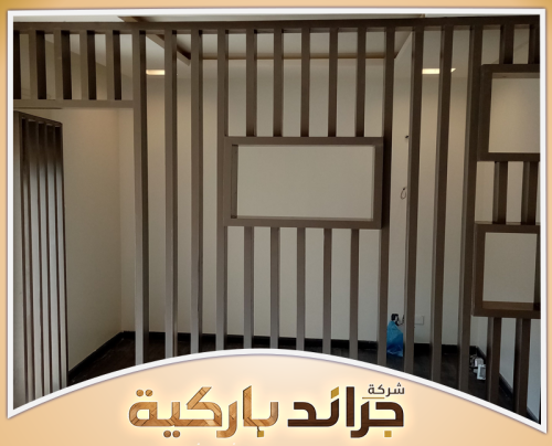 بارتشن خشب بالرياض | 0542860739 جراند باركيه بارتشن خشبي بشرائح رأسية وفتحات مستطيلة يفصل بين مساحتين داخل منزل حديث بالرياض.